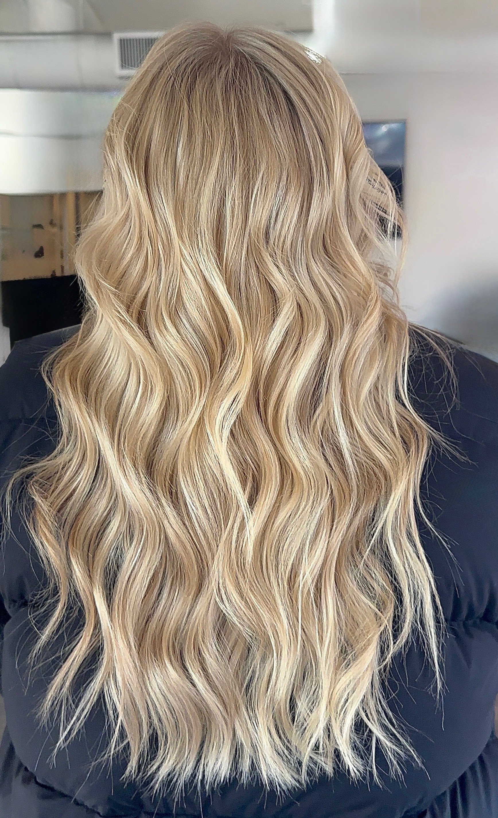 Back view of woman with long, wavy blonde hair.