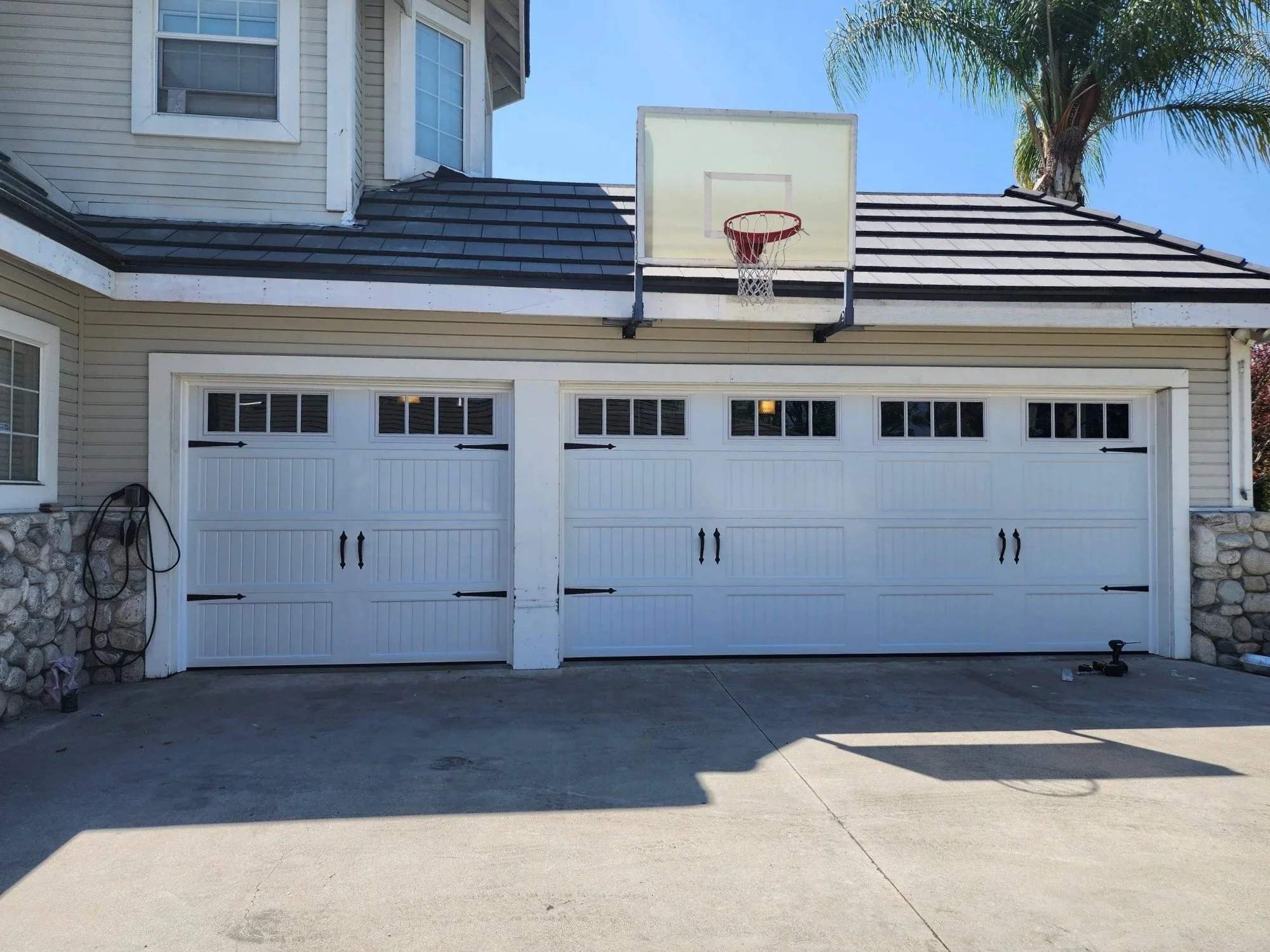 Double garage with white doors, a basketball hoop mounted above, and a concrete driveway in front.