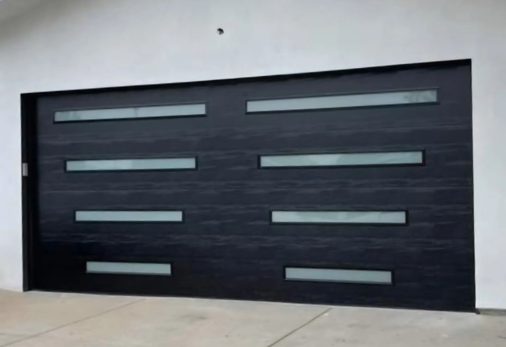 Modern black garage door with horizontal glass panels in a contemporary home.