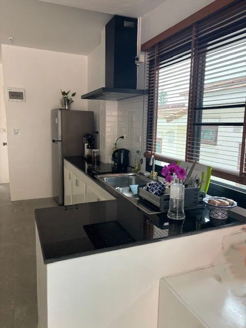 Kitchen with black countertops, white cabinets, stainless steel appliances, and window blinds