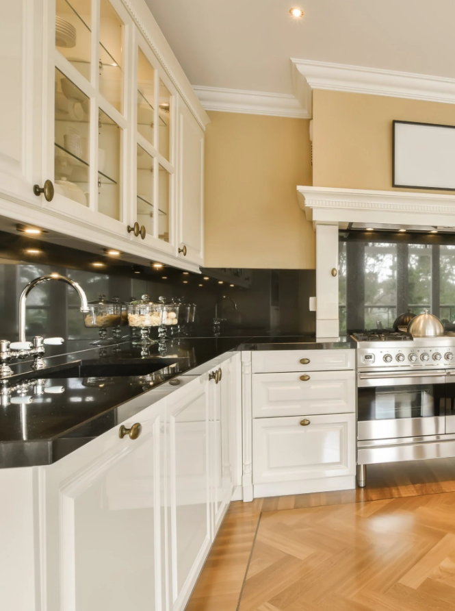 Kitchen with white cabinets, black countertop, and stainless steel stove in a modern home.