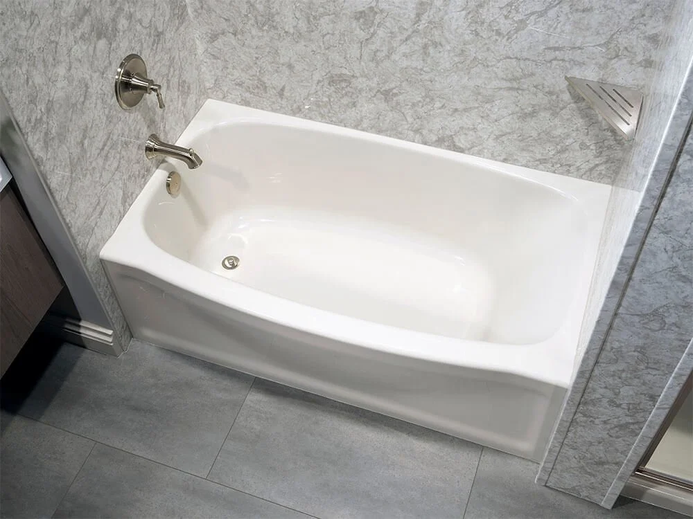 White bathtub with silver faucet in a modern bathroom with gray tile walls and floor.