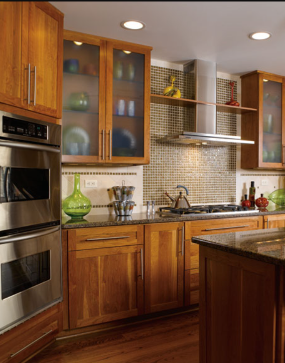 Kitchen with wooden cabinets, stainless steel oven, green decorative vases, and a granite countertop.