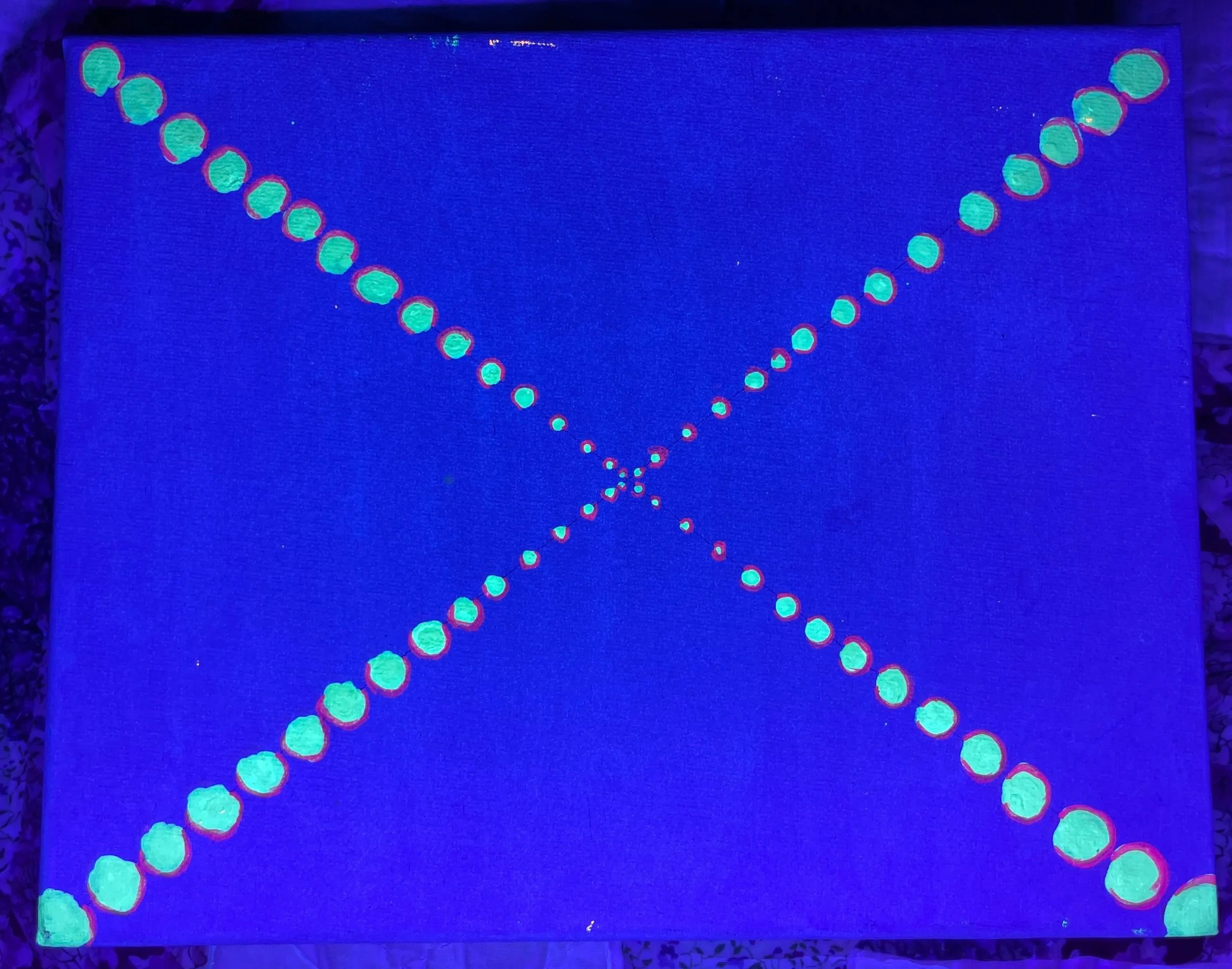 Bastet's Dream - Devotional painting illuminated under blacklight, showing fluorescent dots forming an “X” shape. The dots are light blue with purple halo outlines, larger at the edges and smaller toward the center, creating illusion of falling inwar