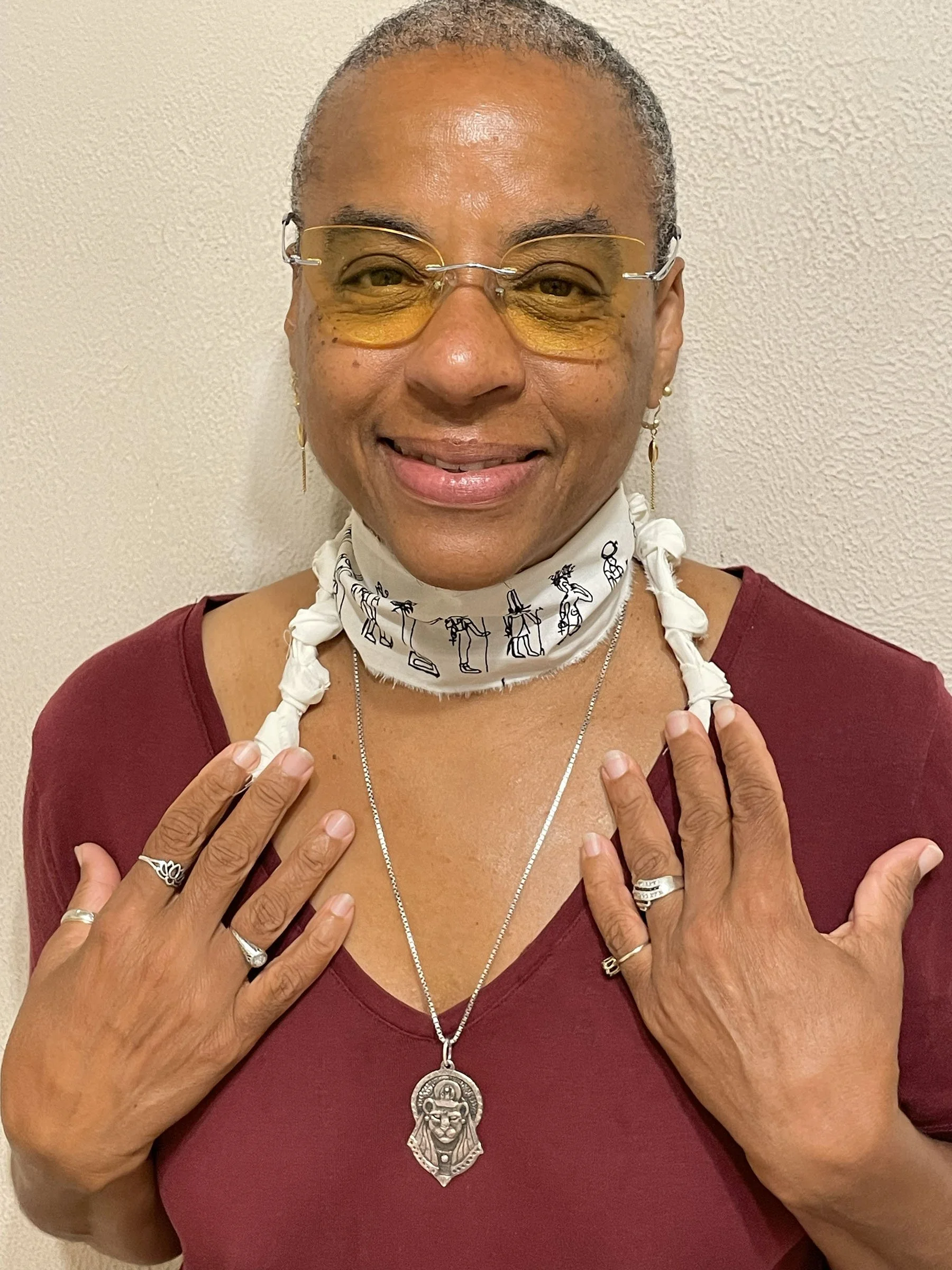 Ali Montgomery wearing a linen scarf around her neck decorated with drawings of Egyptian deities for the Epagomenal days.