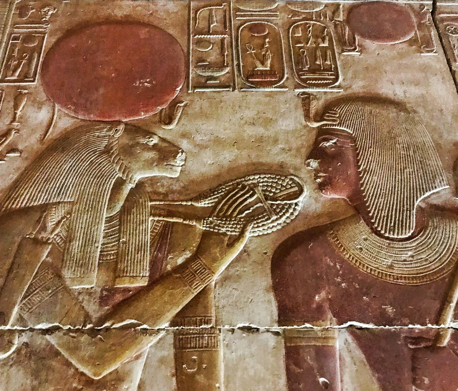 Relief carving of the lion‑headed Goddess Sekhmet touching an ankh and menat to Pharaoh Seti I’s face in the traditional gesture of conferring the breath of life and divine protection.