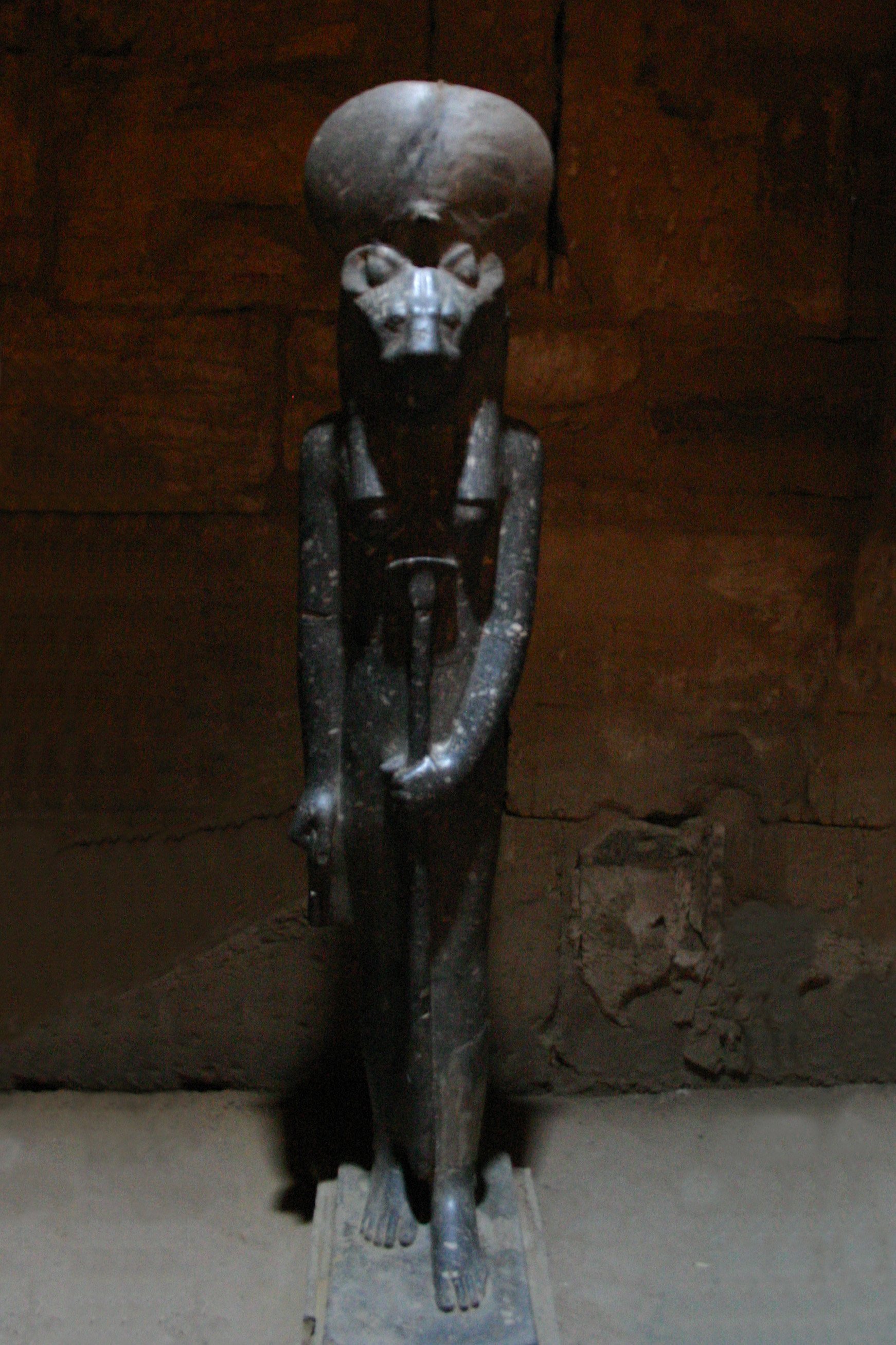 Black stone statue of the lion‑headed Goddess Sekhmet standing in the Temple of Ptah, holding the sekhem staff and ankh, with the udjat cobra and aten disk on Her crown.