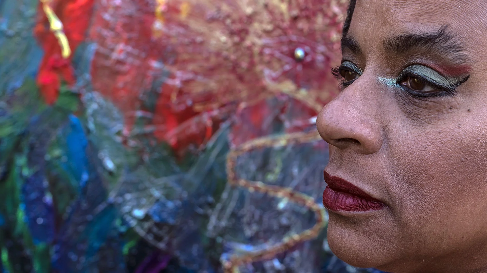 Closeup face of artist and priestess Ali Montgomery photographed in front of her devotional painting.