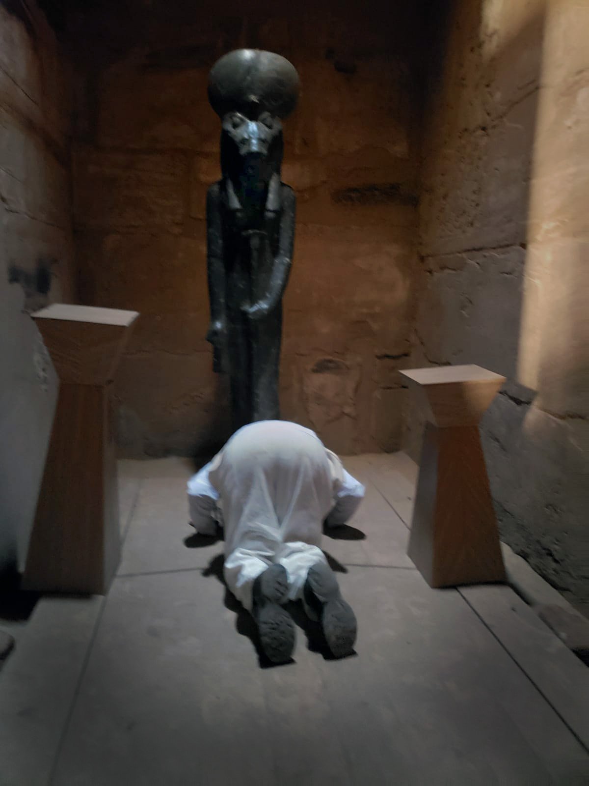 Ali Montgomery bowing in white before the lion‑headed Goddess Sekhmet in the Sekhmet chapel at Karnak.