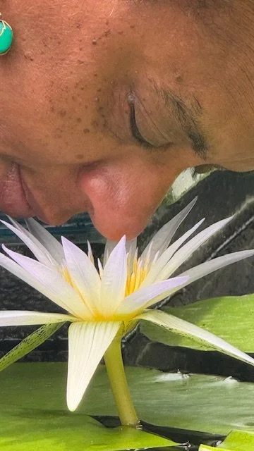 Close up of woman with nose hovering over center of blooming lotus flower.