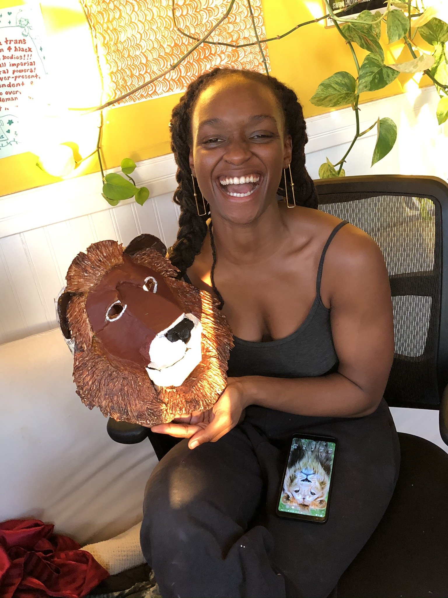 Lanise McKenzie smiling and holding a painted lioness face mask.