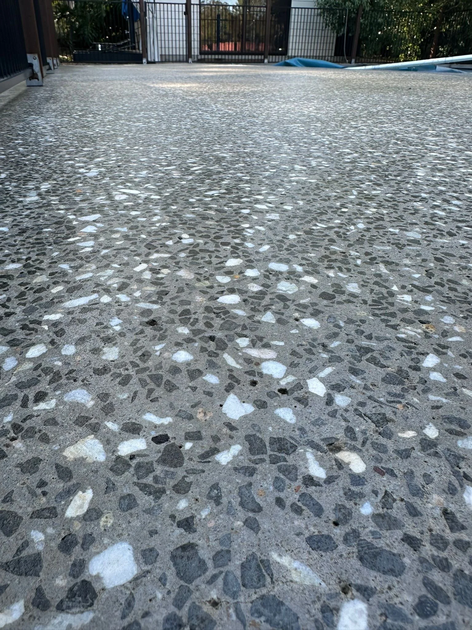 Close-up view of Washworks High Pressure treatment on a honed textured concrete surface (with embedded small stones and pebbles)