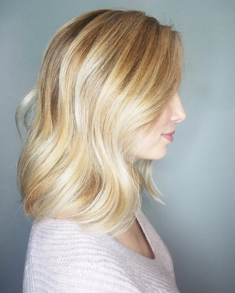 Side profile of a woman with shoulder-length, blonde hair styled in loose waves.