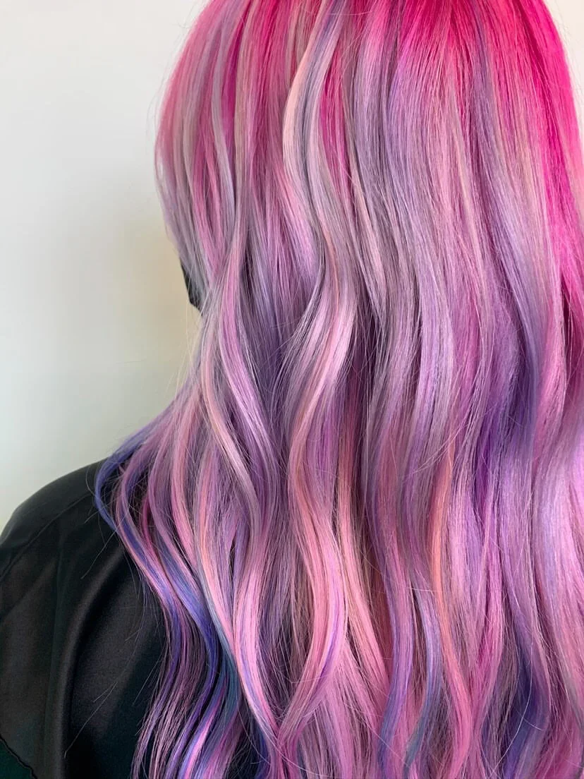 Close-up of long, wavy hair dyed in shades of pink, purple, and blue.