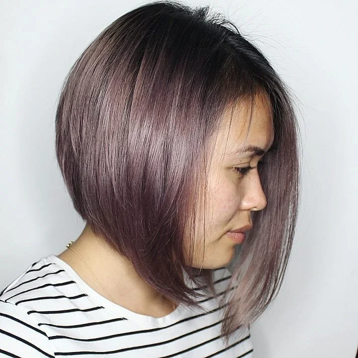 Woman with a sleek, shoulder-length layered bob hairstyle dyed in shades of purple and gray.