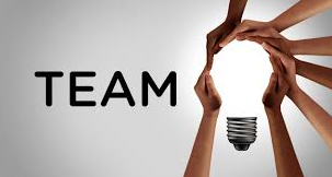 Multiple hands joining together above a light bulb with the word 'TEAM' in bold black letters on a gray background