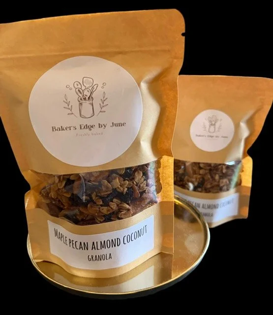 Two resealable pouches of Maple Pecan Almond Coconut Granola with a white label and black text, set on a reflective surface against a black background.