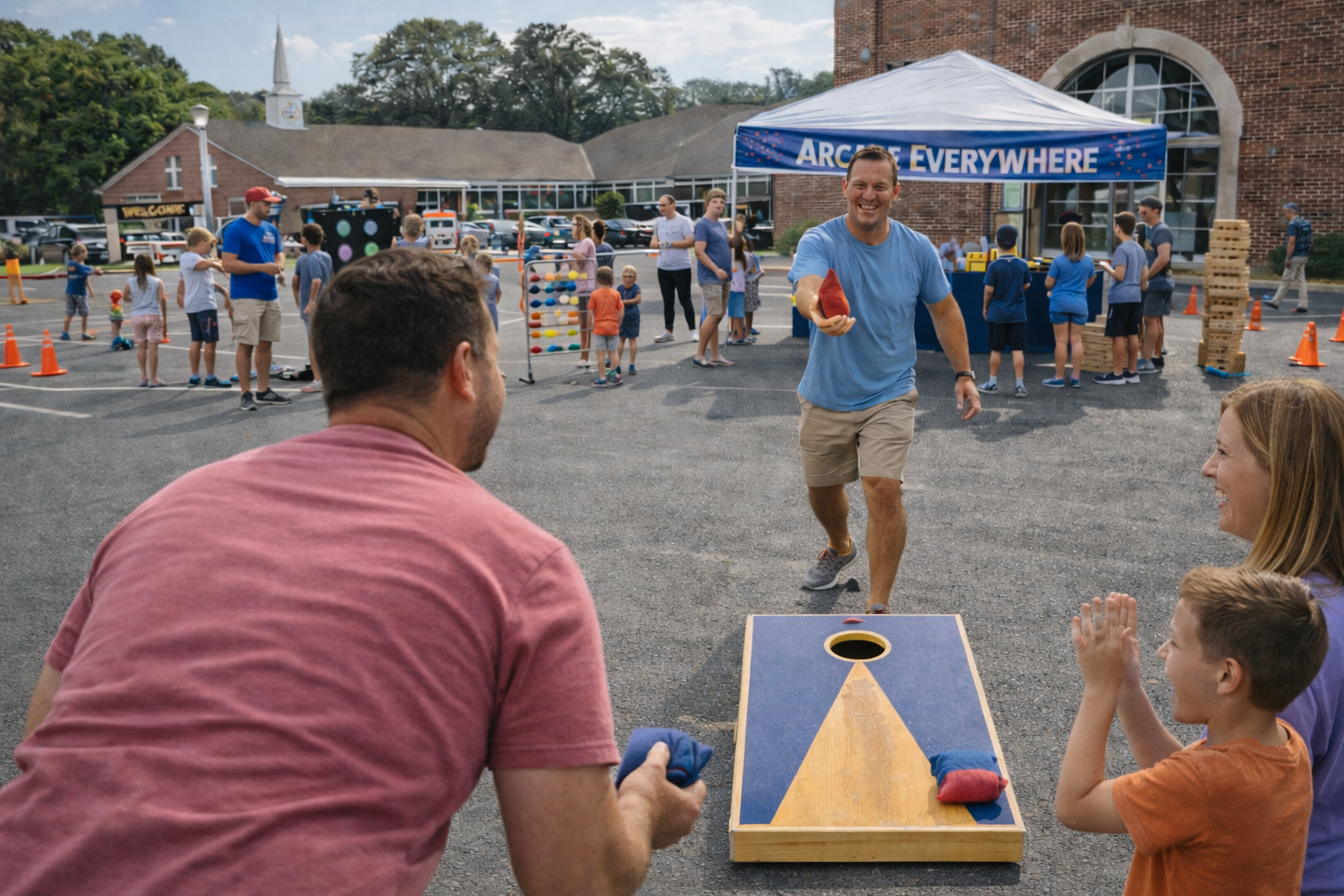 People playing a bean bag toss game at an outdoor fair, with children and adults engaging in activities under a blue canopy that reads 'ARCADE EVERYWHERE'.
