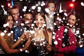 Group of diverse young women celebrating with confetti at a party or New Year's Eve celebration.