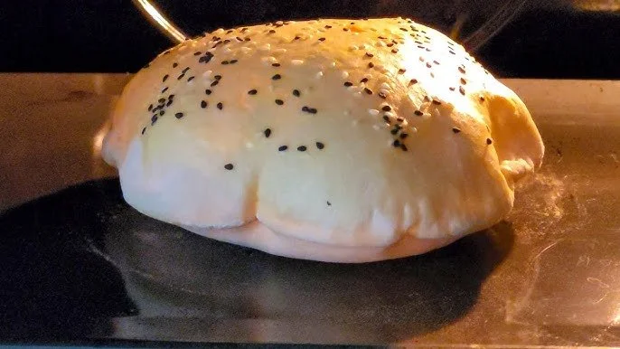 Baked bread with black sesame seeds on top inside an oven.