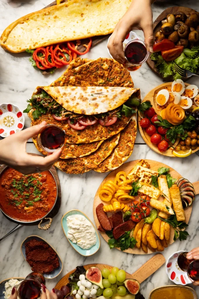 Variety of Middle Eastern dishes including flatbread, stuffed bread, grilled meats, salads, boiled eggs, and grapes on a marble table.