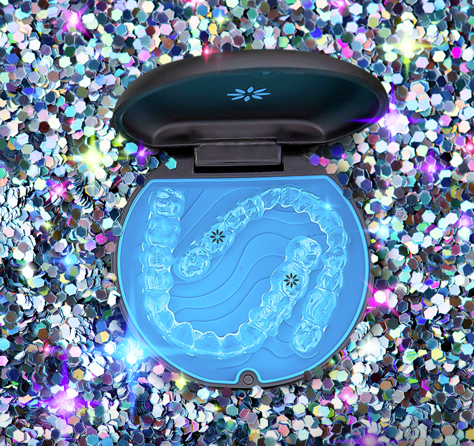 Open dental aligner case with clear aligners inside, placed on holographic digital x-ray of teeth, surrounded by colorful, reflective glitter background.