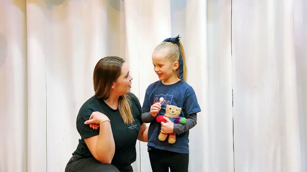 Professional musical theatre teacher guiding a child during a rehearsal