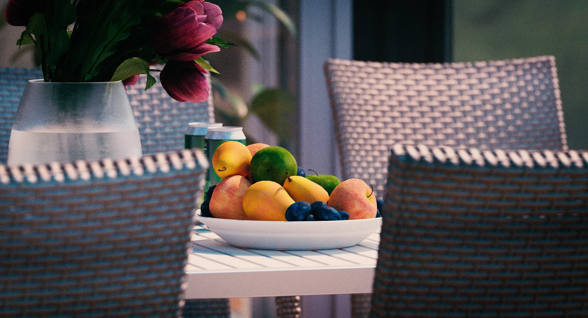 A table with a bowl of assorted fruits including apples, pears, grapes, and a lime, with a vase of pink flowers and cans in the background.