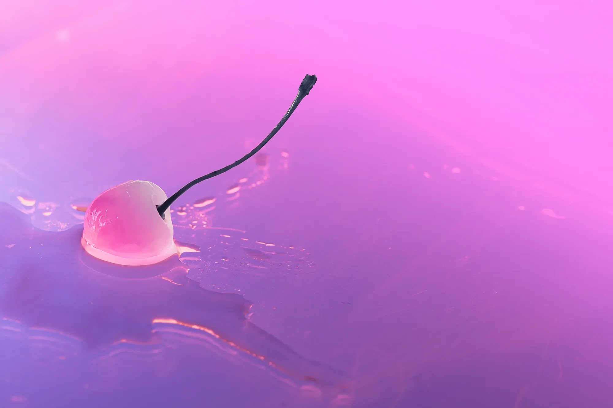Close-up of a lit matchstick with a pink wax pool and a flickering flame, reflected on a smooth surface with pink and purple hues.