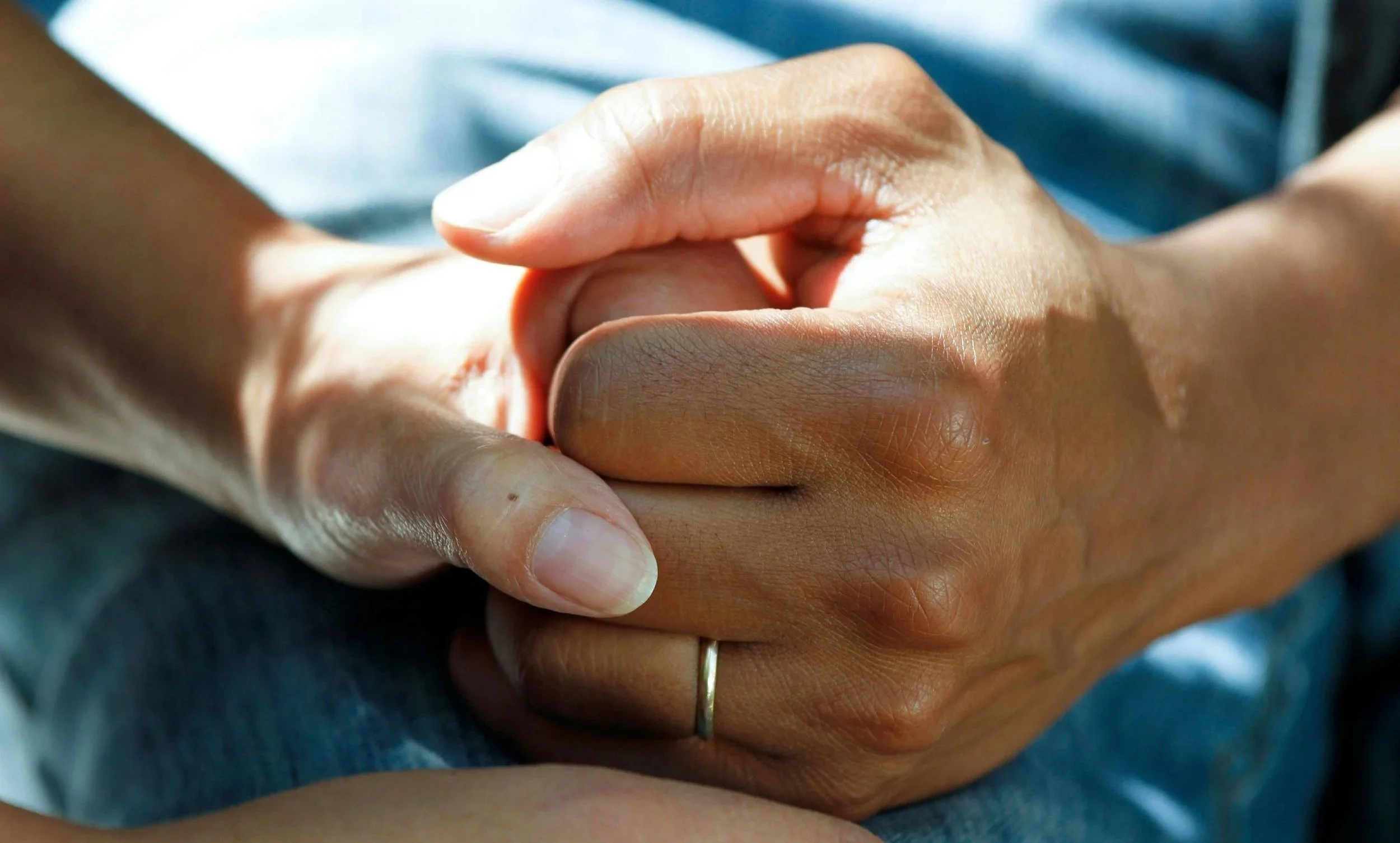 Close-up of two hands clasped together, one hand belonging to a healthcare professional.