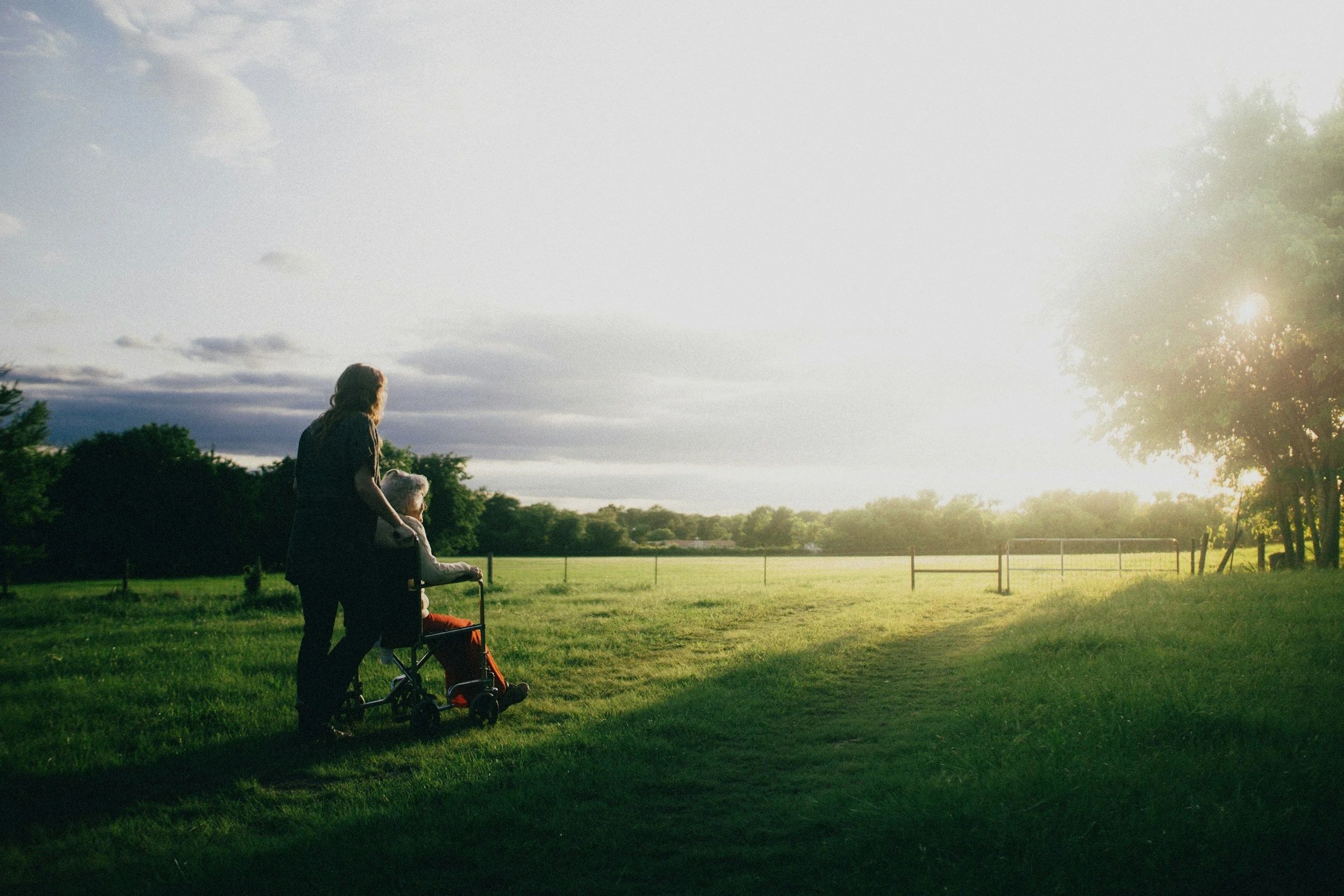 A healthcare professional pushing an elderly person in a grassy field in Centerville, Ohio.