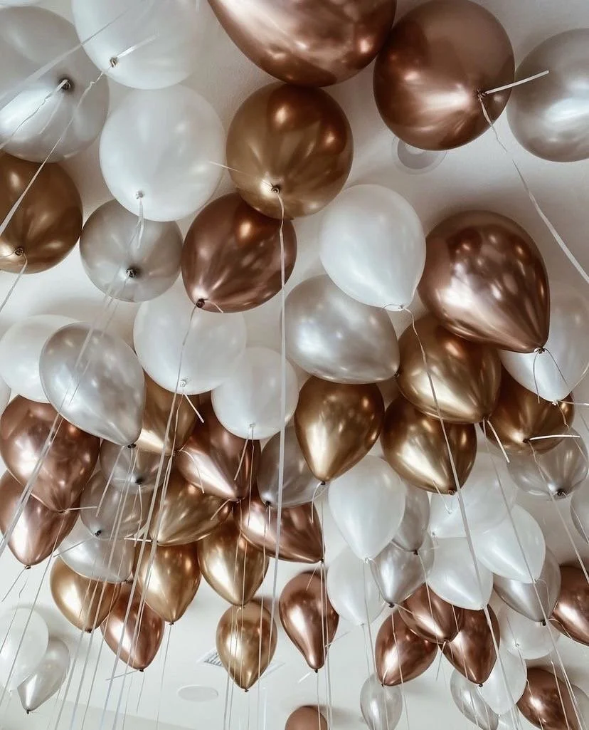 A ceiling decorated with numerous metallic and white balloons in gold, silver, and pearl finishes.