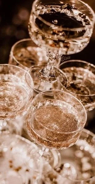 Close-up of multiple glasses filled with sparkling wine, with one glass raised for a toast.
