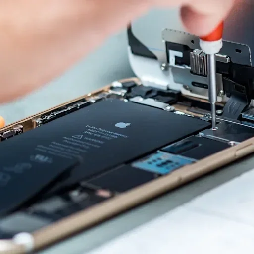 A technician repairing a smartphone with the back cover removed, exposing internal components, and using a screwdriver.