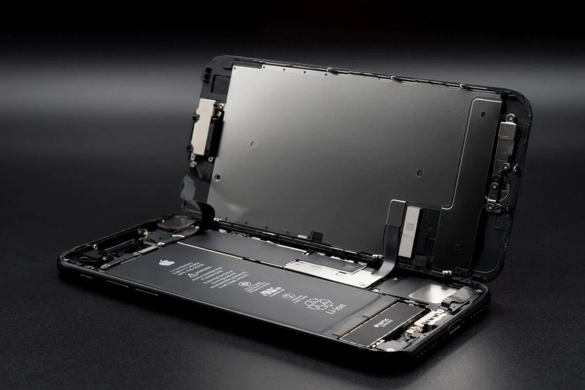 Open iPhone with internal components and battery visible on a black surface.