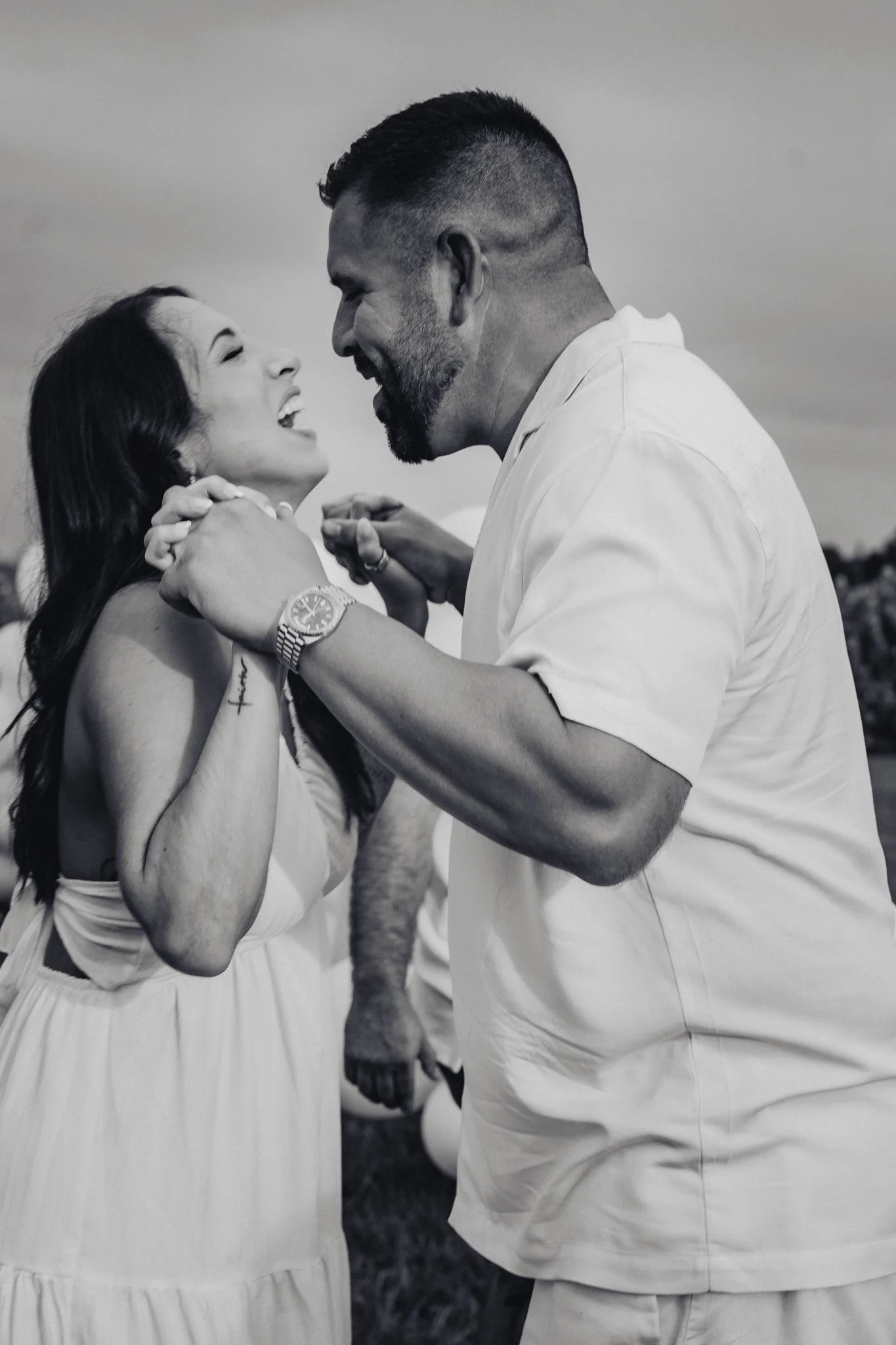 A couple smiling and embracing outdoors, black and white photograph.