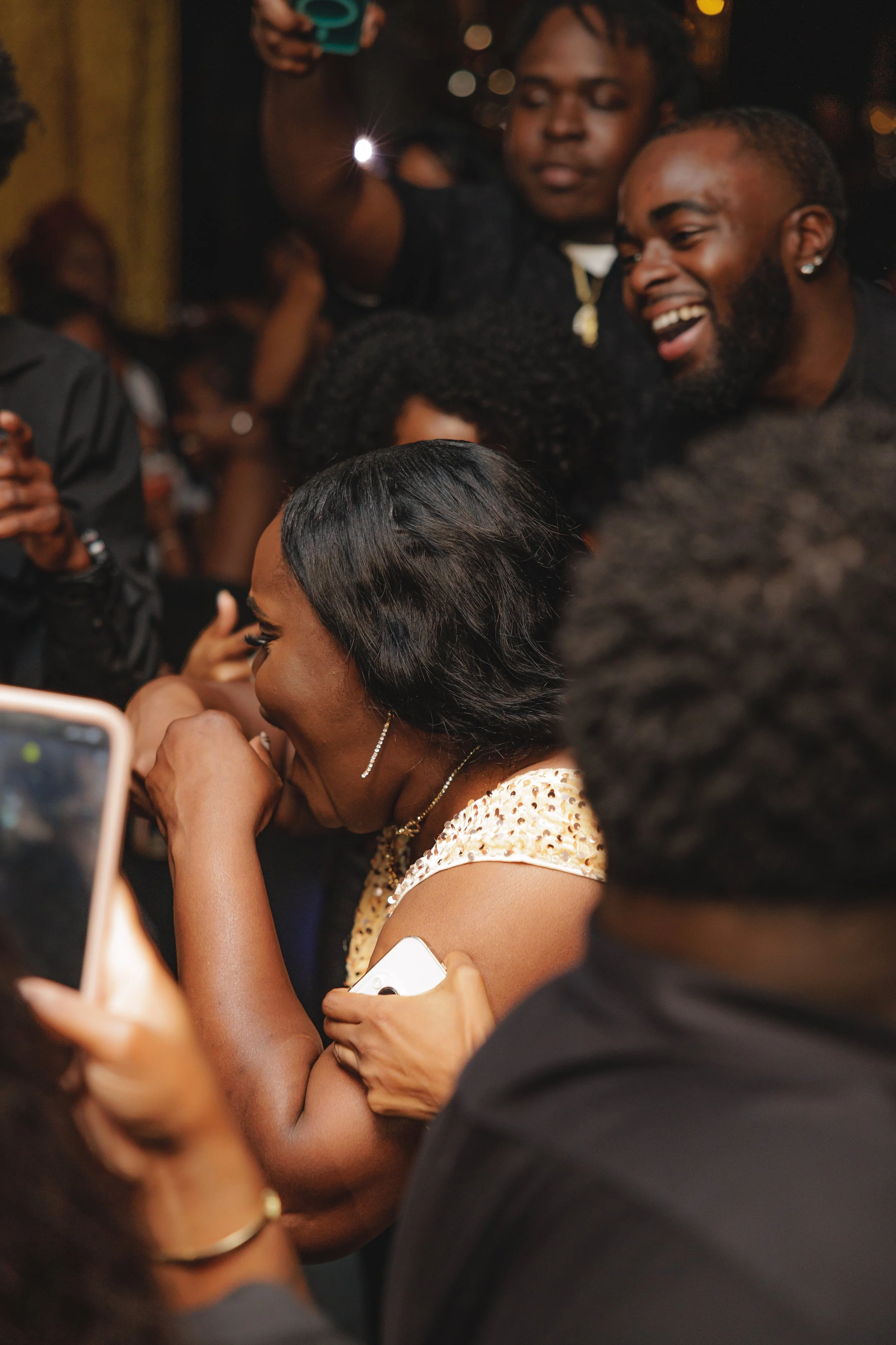 A woman is crying and laughing while surrounded by smiling people at a celebration or party.