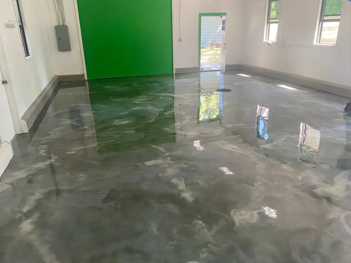 Empty room with polished concrete floor, green wall, and windows allowing natural light.