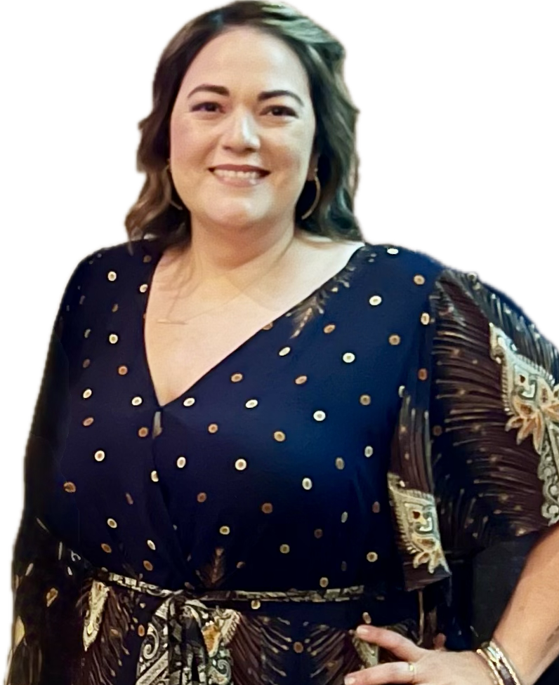 A woman with shoulder-length hair, smiling, wearing a dark dress with gold polka dots and patterned sleeve details, standing against a background with bright black, yellow, and red colors.