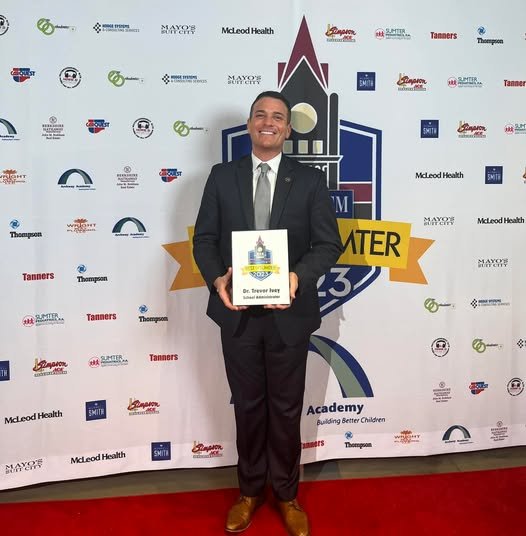 Dr. Trevor Ivey poses on the red carpet holding an award at Best of Sumter event.