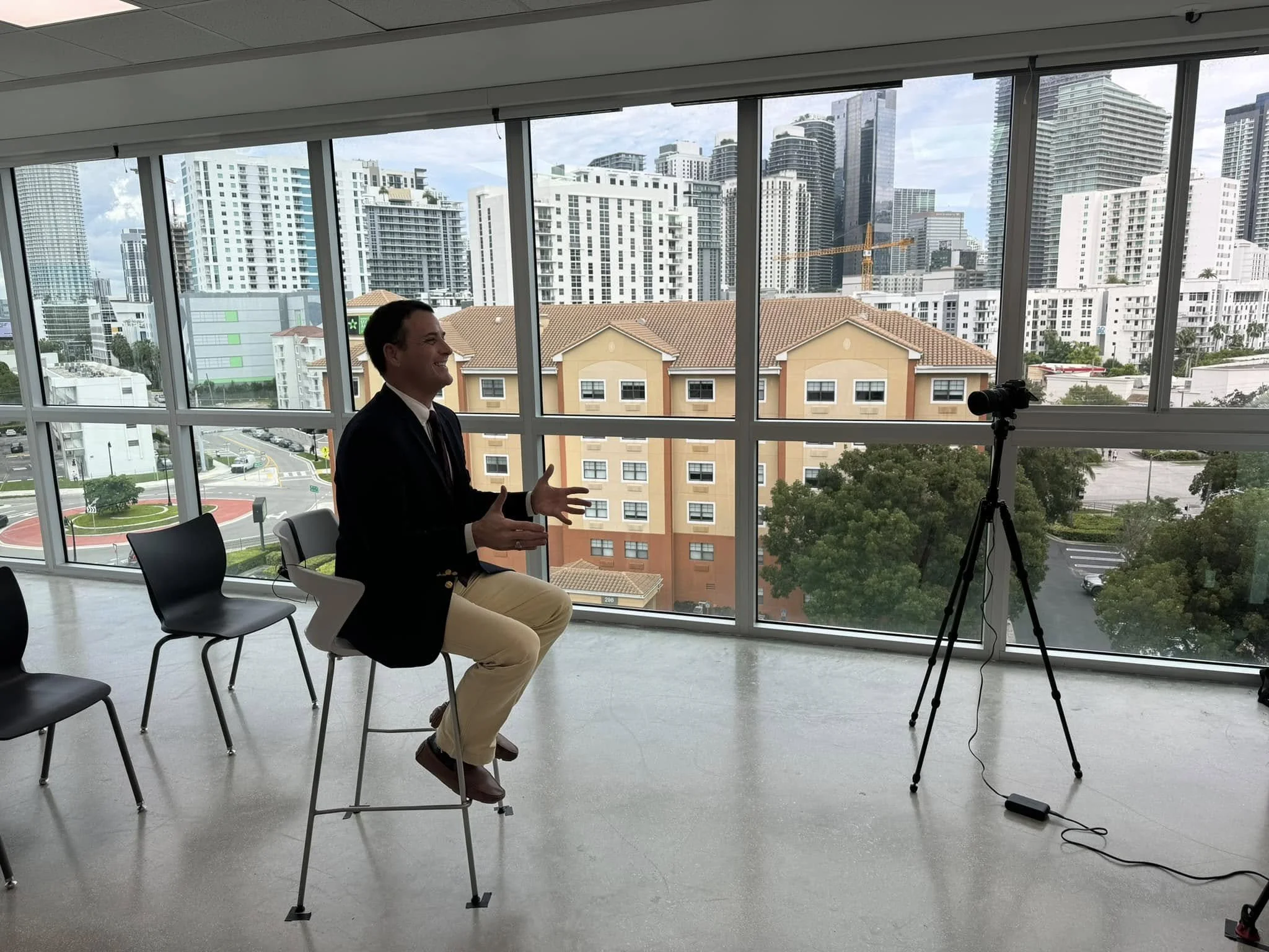 Dr. Trevor Ivey sits for a video interview with a cityscape backdrop behind him.