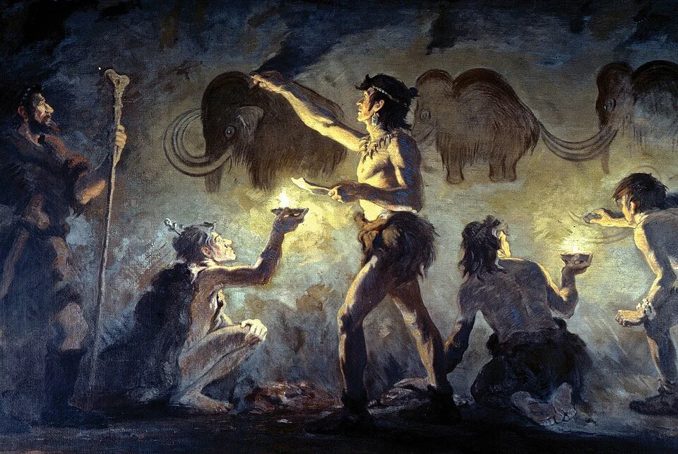 A painting depicting a prehistoric scene with early humans around a fire, surrounded by mammoths, with one human holding a spear and others holding bowls or gesturing.