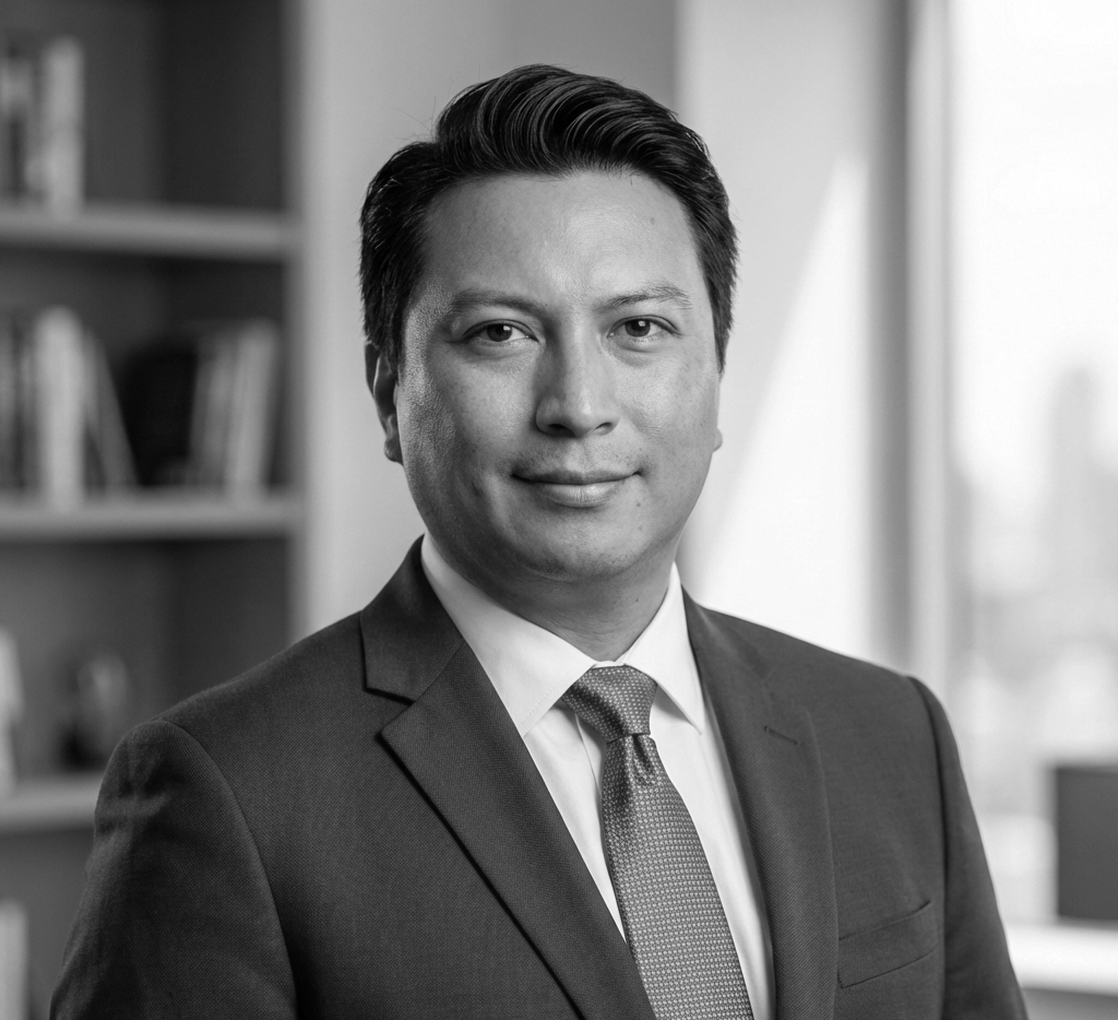 Black and white professional portrait of a man in a suit and tie, in an office setting.
