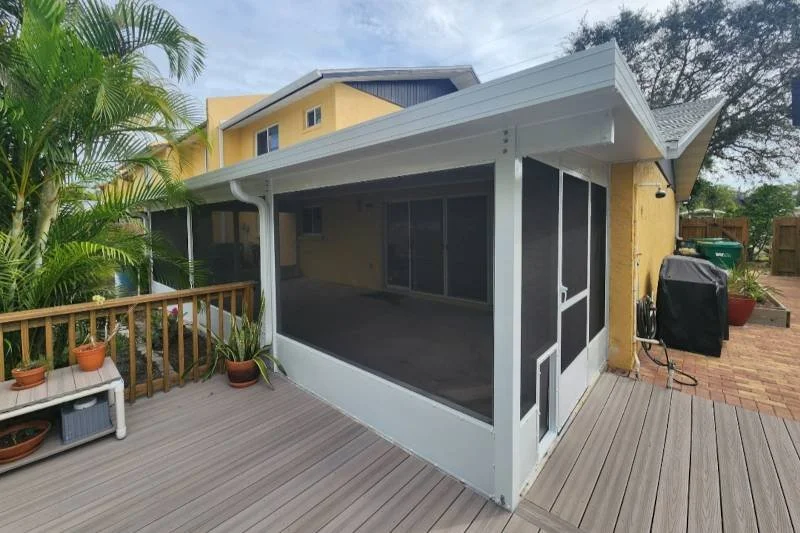 Backyard patio with screened-in porch, potted plants, and a wooden fence.