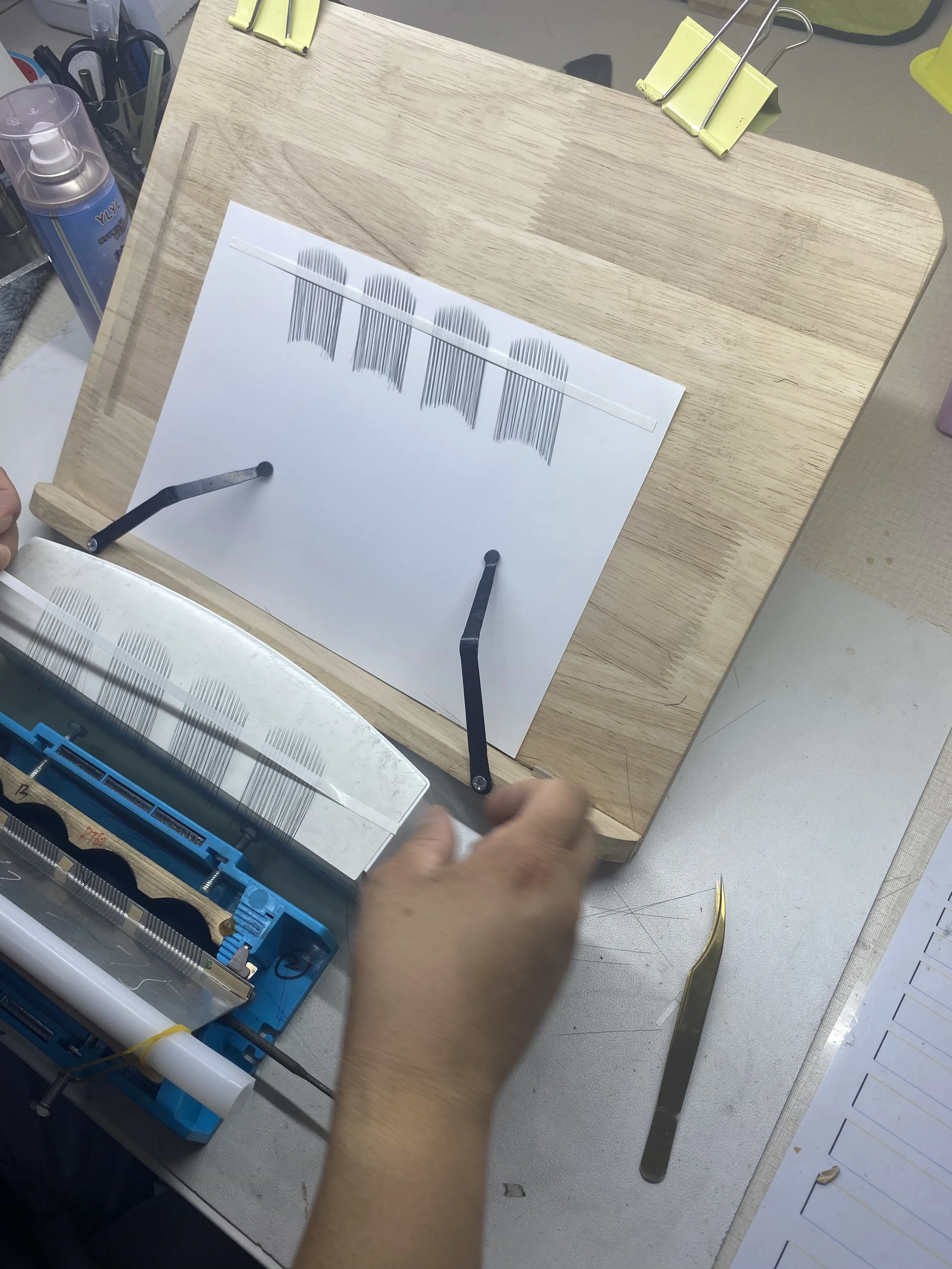 A person is working on a barcode scanner printing test on a piece of paper, mounted on a wooden surface with tools and equipment around.