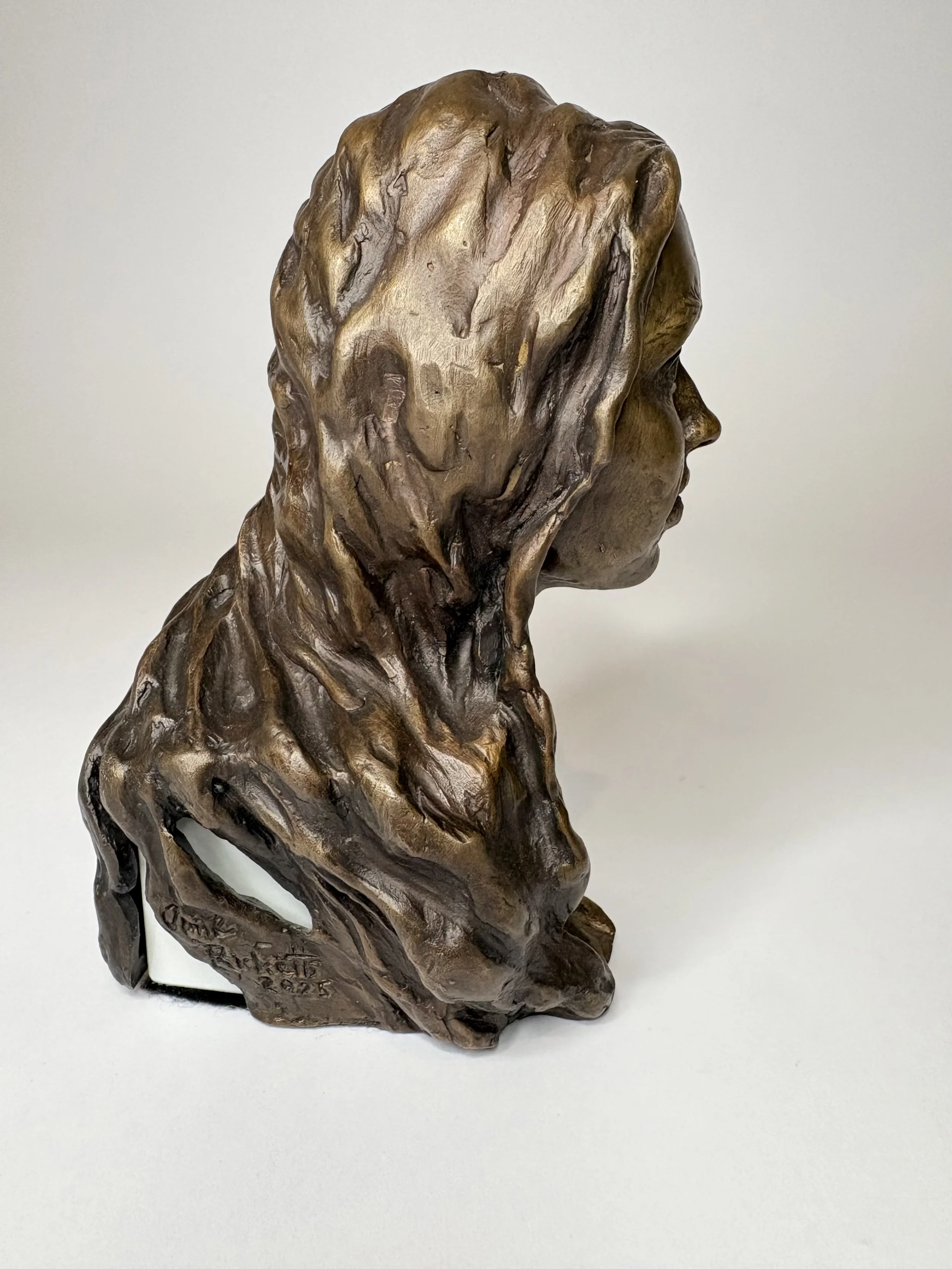 Bronze bust sculpture of a woman in profile view.