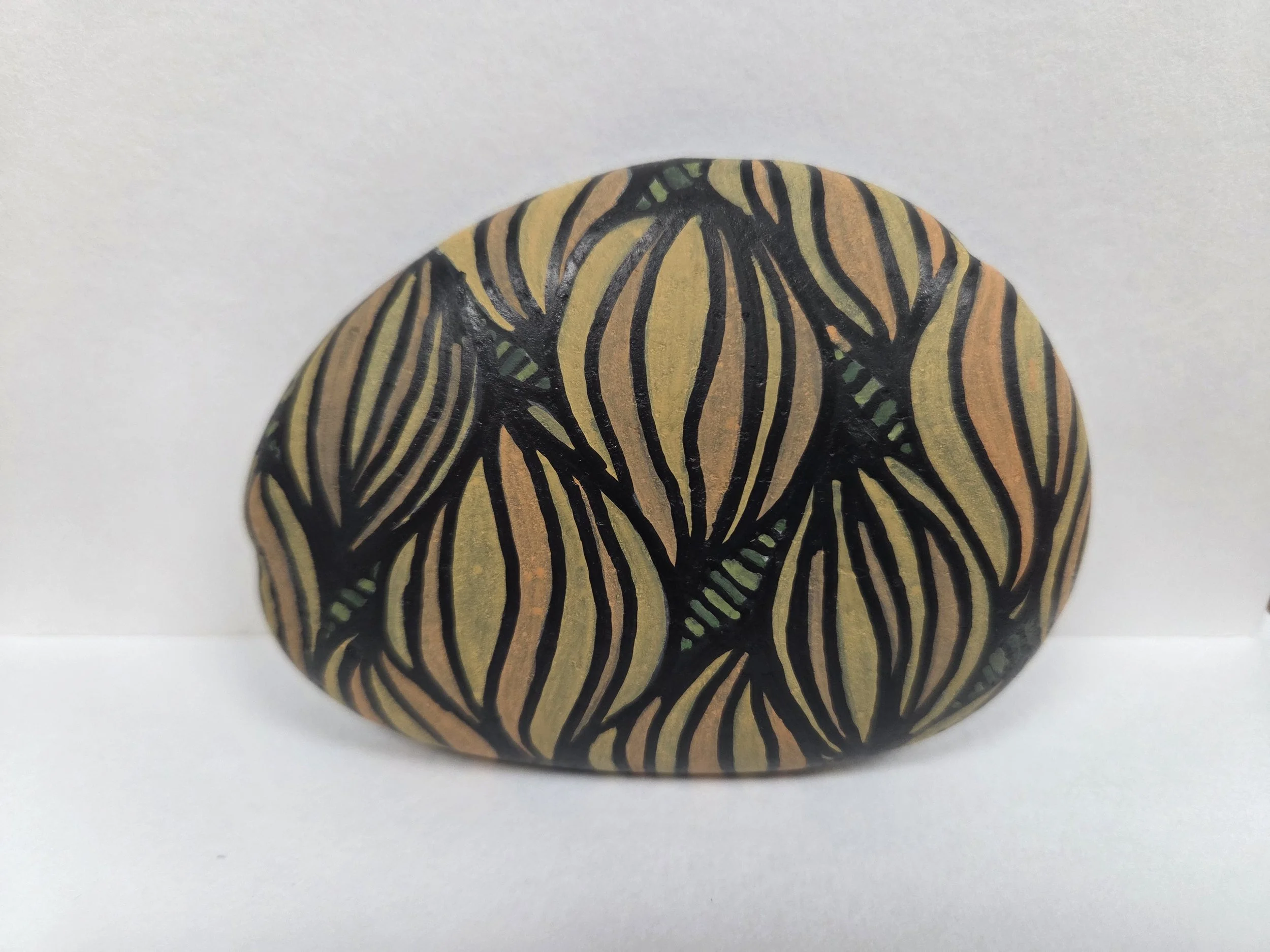 A painted rock with intricate black, yellow, and orange striped patterns.