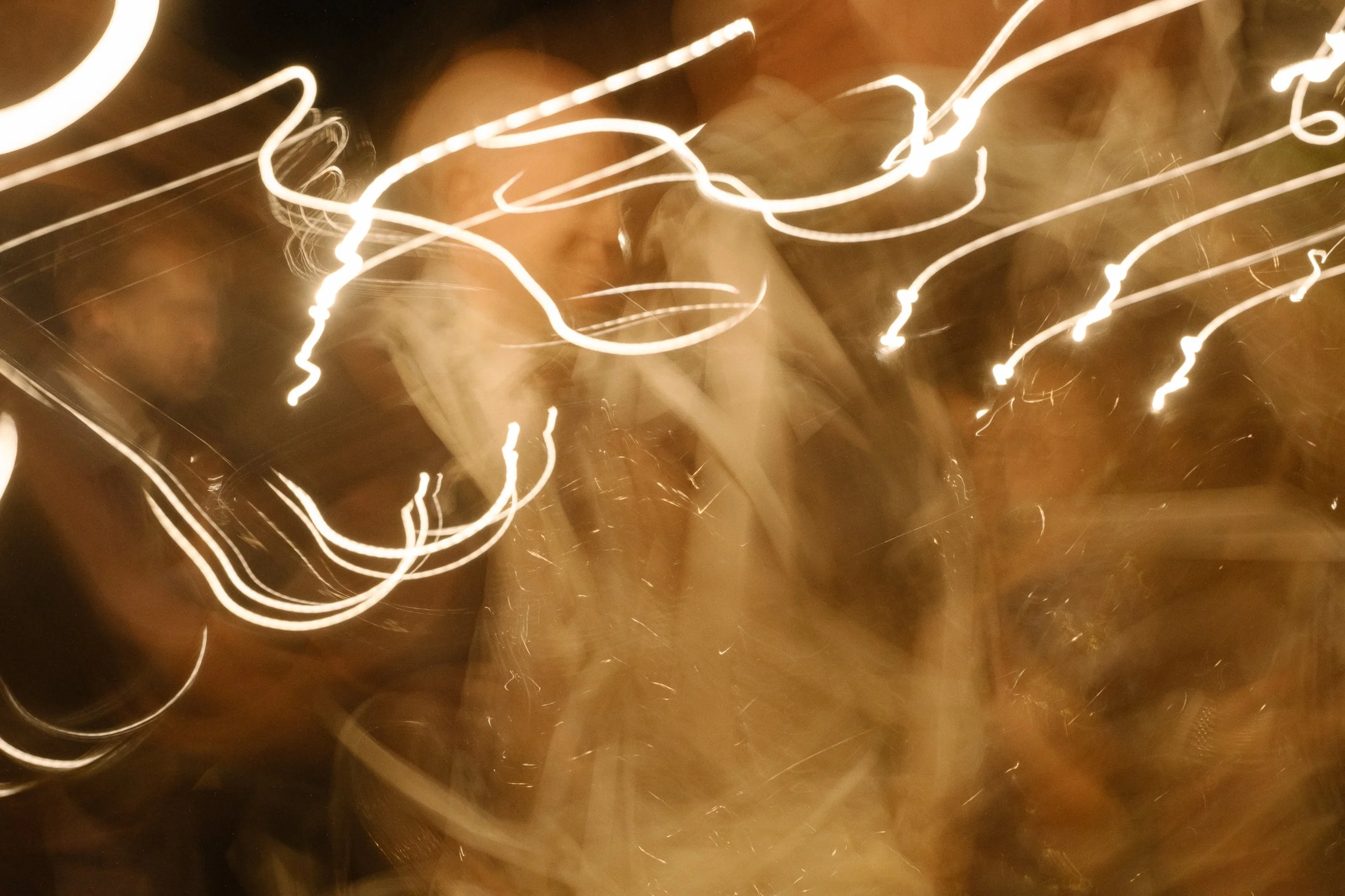 Abstract photo with light trails and blurred figures at night, possibly in a lively setting.