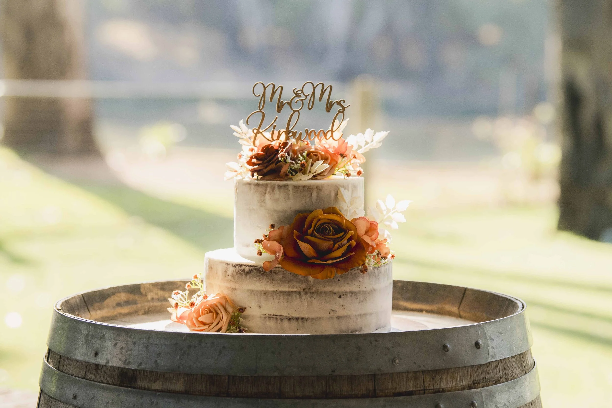 A wedding or celebration cake decorated with flowers and a topper 