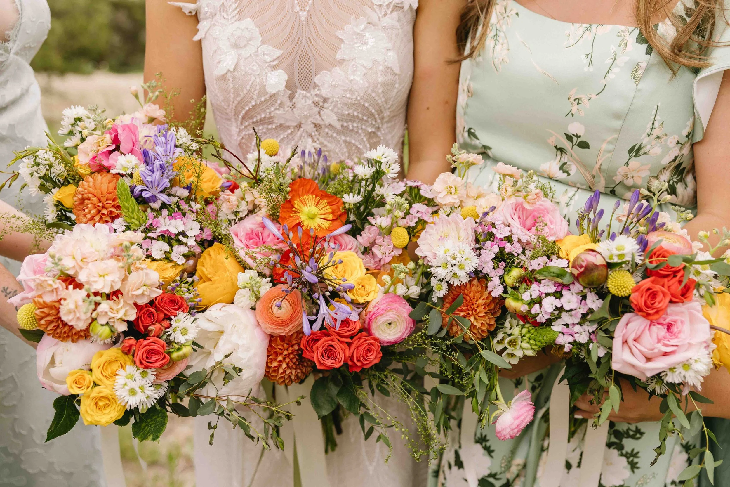 Several women are holding bouquets of colorful flowers, including roses, ranunculus, daisies, and other mixed blooms, during a celebration or event.